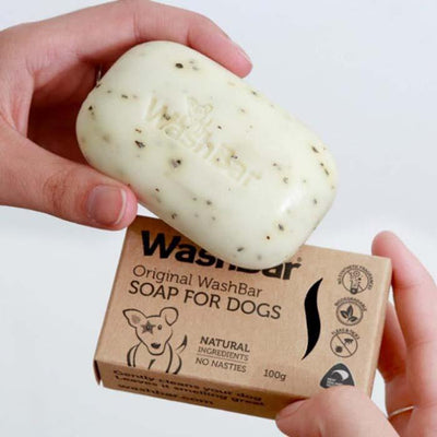 A picture of a hand holding a bar of WashBar original dog soap and shampoo